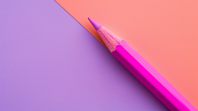 A purple colored pencil positioned diagonally along the boundary where a lavender surface meets an orange one, illustrating the concept of negative space.